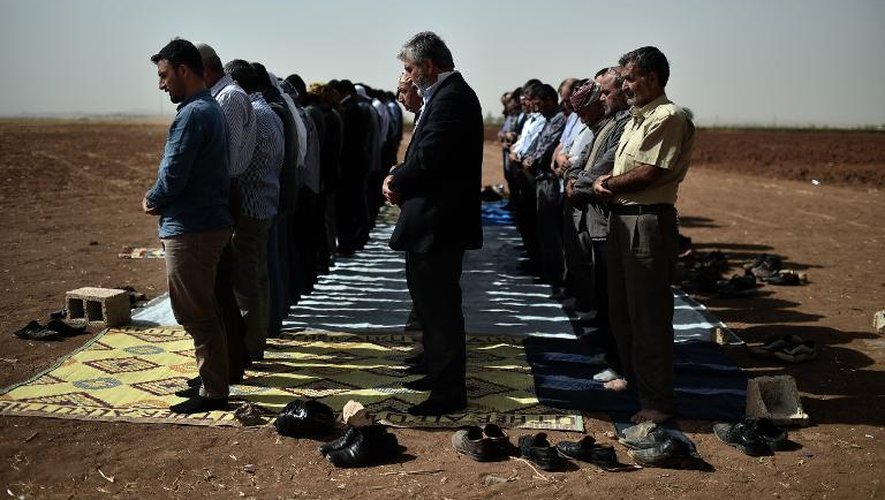 Des Kurdes syriens et turcs prient à Suruc, de l'autre côté de la frontière, en face de Kobané, le 10 octobre 2014