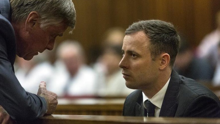 Oscar Pistorius (d) discute avec l'un de ses avocats à la reprise de son procès le 13 octobre 2014 à Johannesburg