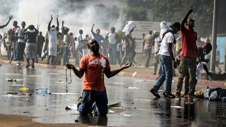 Un partisan de l'opposition gabonaise prie devant les forces de l'ordre à Libreville lors d'une manifestation de l'opposition contre la réélection d'Ali Bongo, le 31 août 2016