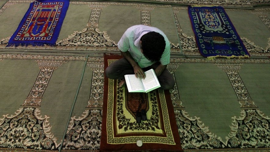 Un homme lit le Coran sur un tapis de prière dans une mosquée de Bagdad, le 16 juillet 2012