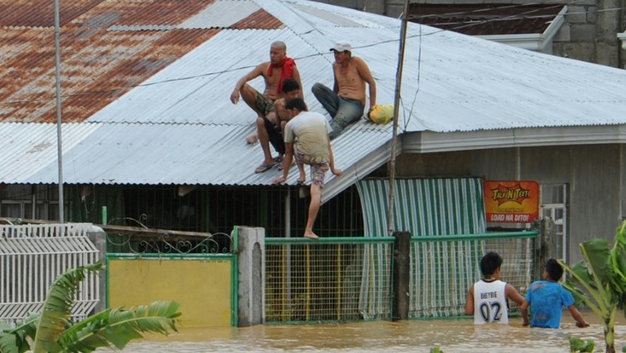 Des habitants trouvent refuge sur le toit de leur maison, le 19 octobre 2015 lors du passage du typhon Koppu sur la ville de Santa Rosa, au nord de Manille