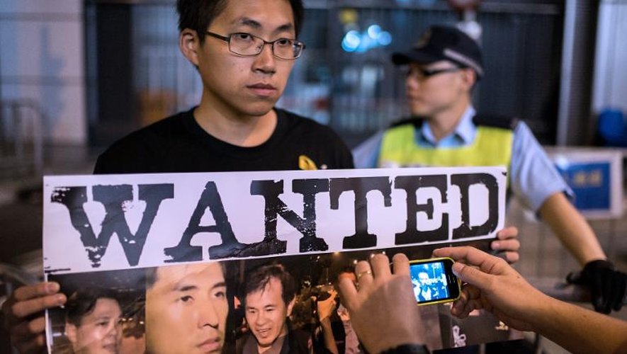 Un homme montre une affiche avec les photos des moliciers accusés d'avoir battu un manifestant, le 15 octobre 2014 à Hong Kong