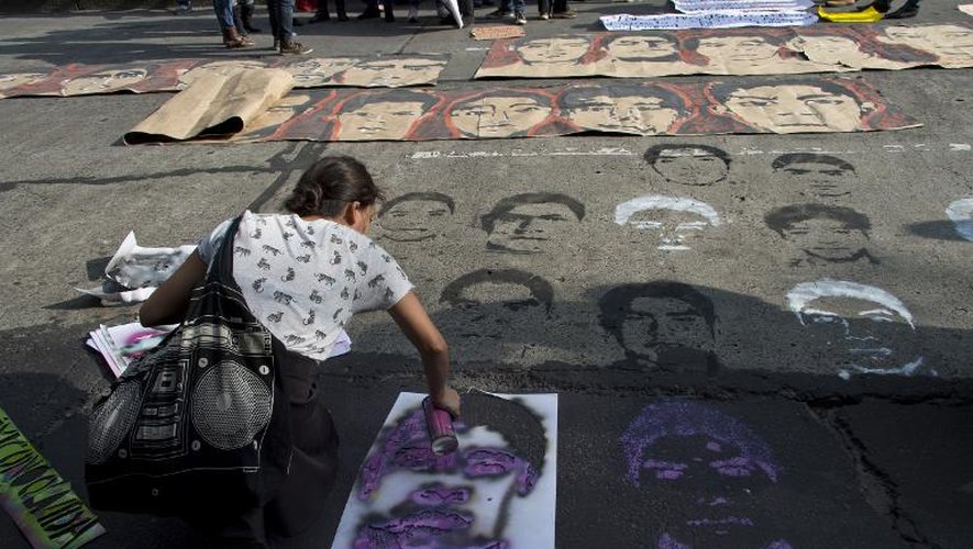 Une étudiante peint au pochoir sur un trottoir les visages des 43 étudiants disparus devant les bureaux du ministre de la Justice, le 15 octobre 2014 à Mexico