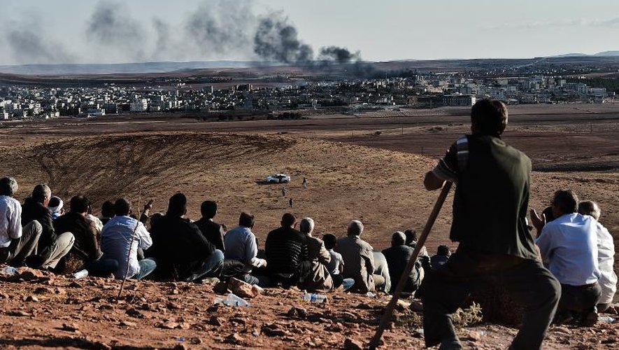 Des Kurdes regardent la fumée au-dessus de la ville de Kobané lors de frappes aériennes de la coalition, depuis une colline à Mursitpinar, le 15 octobre 2014, à la frontière syro-turque