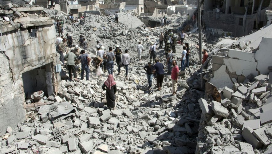 Des habitants au milieu des décombres d'un quartier de la ville d'Alep, le 21 juillet 2015