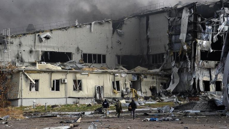 Des rebelles prorusses et des journalistes courent s'abriter lors d'un bombardement  de l'aéroport de Donetsk, à l'est de l'Ukraine, le 16 octobre 2014