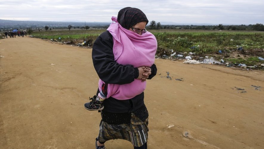 Une femme tient son bébé contre elle en traversant la frontière entre la Macédoine et la Serbie le 21 octobre 2015 près du village de Miratovac