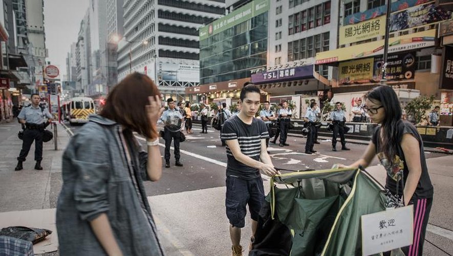 Des manifestants pro-démocratie plient bagage sous l'oeil des policiers le 17 octobre 2014 dans le quartier de Mongkol à Hong Kong