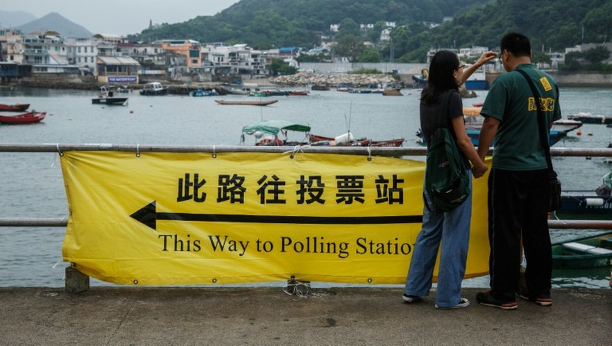 Un couple devant une banderole indiquant la direction des bureaux de vote, à Hong Kong le 4 septembre 2016