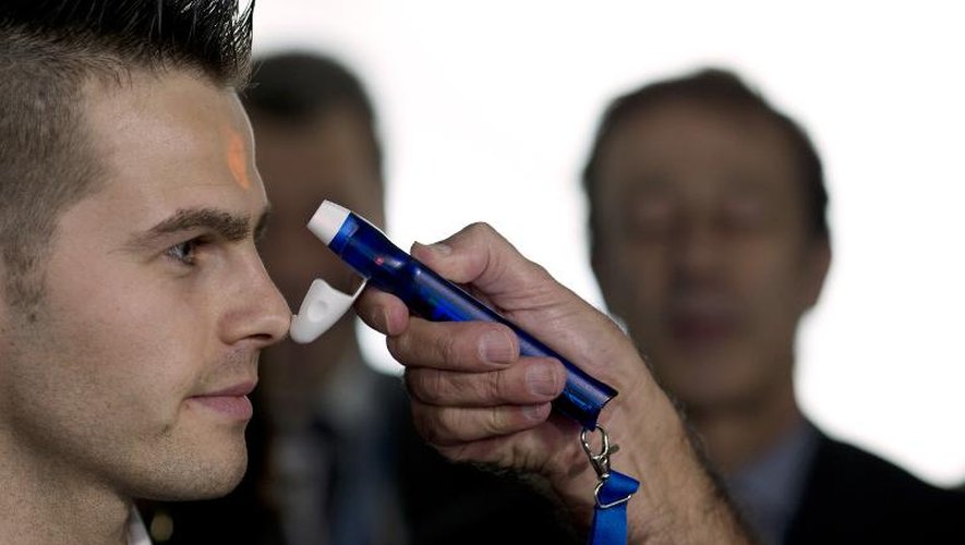 Un employé de l'aéroport pratique un test avec un thermomètre à Roissy le 17 octobre 2014