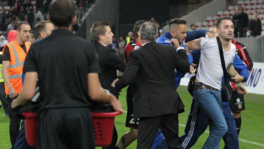 Un supporter niçois (à droite) est expulsé après être entré sur le terrain à la fin du match Nice-Bastia à Nice le 18 octobre 2014