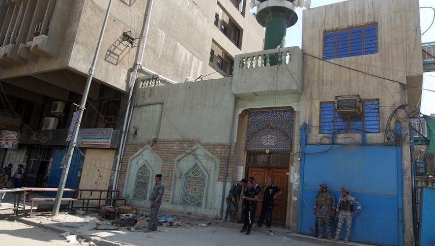 Des policiers irakiens inspectent le 27 mai 2014 les lieux d'un attentat à la bombe qui a fait 13 morts à l'extérieur d'une mosquée chiite à Bagdad