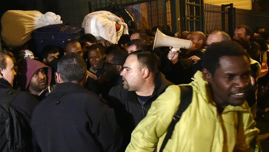 Des migrants quittent leur camp de fortune dans le lycée désaffecté Jean-Quarré à Paris le 23 octobre 2015, après une évacuation par la police
