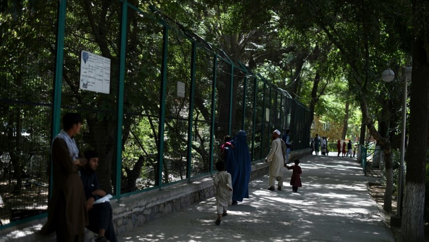 Des visiteurs se promènent à l'ombre des arbres dans les allées du zoo de Kaboul, le 12 juillet 2016 en Afghanistan