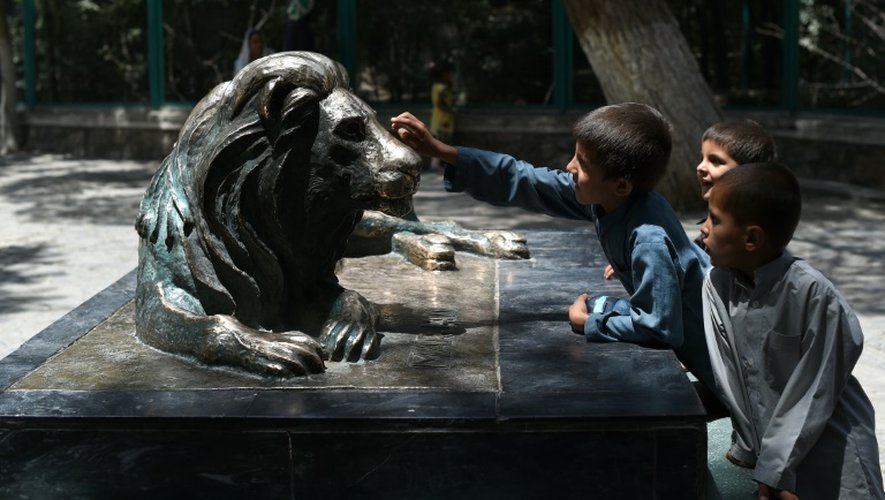 Des enfants afghans touchent la statue de "Marjan", le lion du zoo de Kaboul, symbole de la résilienne afghane, le 12 juillet 2016 à Kaboul