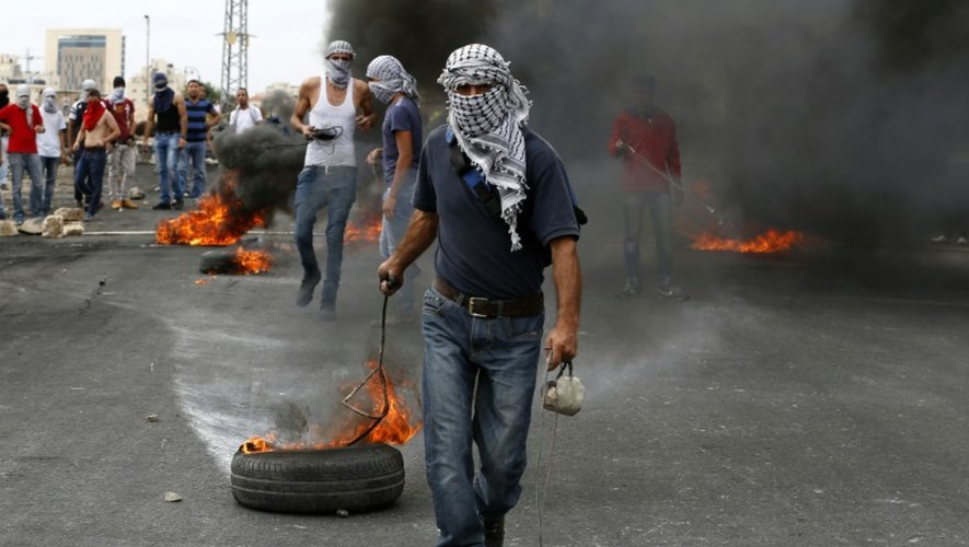 Un palestinien traîne un pneu en feu à Al-Bireh dans la banlieue nord de Ramallah, le 23 octobre 2015