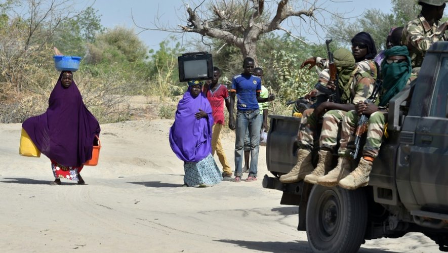 Des soldats nigériens passent devant des personnes qui fuient les islamistes de Boko Haram, le 25 mai 2015 à Malam Fatori