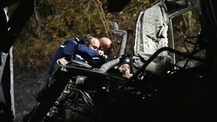 Photo fournie le 23 octobre 2015 par le ministère de l'Intérieur de gendarmes inspectant la carcasse de l'autocar entré en collision avec un camion à Puisseguin