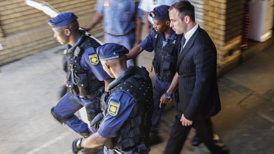 Oscar Pistorius escorté par des policiers le 21 octobre 2014 à sa sortie du tribunal de Pretoria