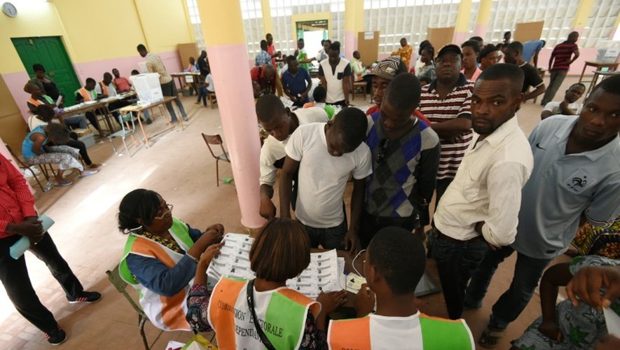 Des agents électoraux vérifient les pièces d'identité des électeurs qui se présentent pour voter à la présidentielle, le 25 octobre 2015 à Abidjan, en Côte d'Ivoire