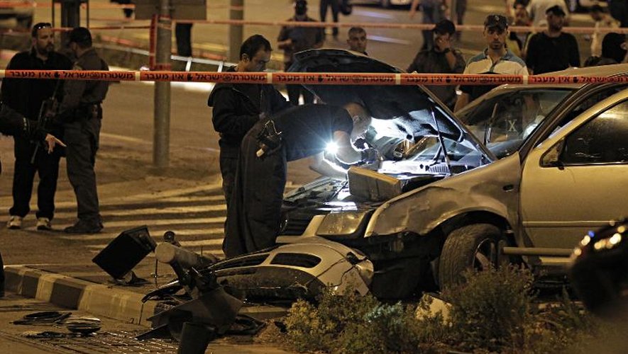 Des policiers israéliens inspectent une voiture qui a été lancée par un Palestinien sur un groupe de piétons, le 22 octobre 2014 à Jérusalem