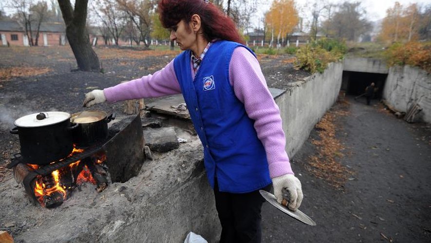 Entre les bombardements, une femme fait la cuisine le 23 octobre 2014 près d'un abri à Donetsk où une centaine de personnes sont réfugiées pour fuir les combats entre rebelles prorusses et forces ukrainiennes