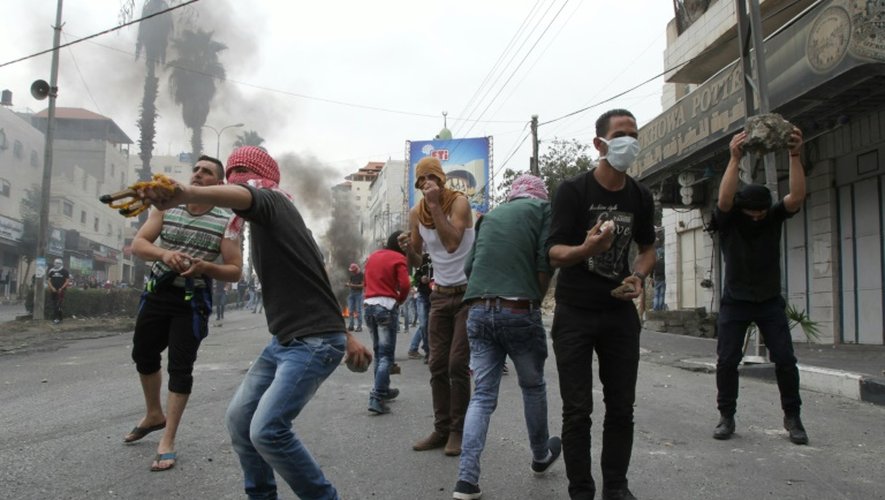 Des Palestiniens jettent des pierres sur des soldats israéliens à Hébron en Cisjordanie, le 26 octobre 2015
