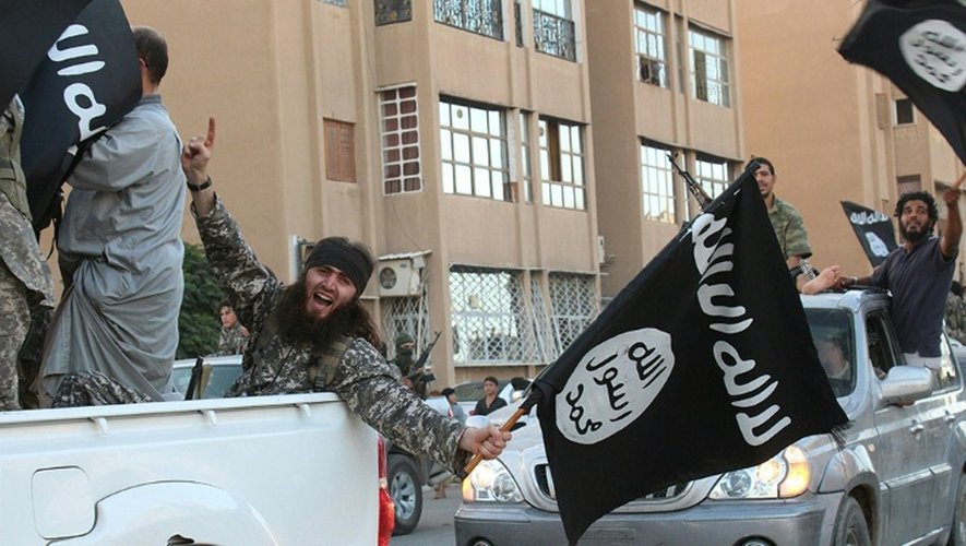 Une image diffusée par l'organe de presse jihadiste Welayat Raqa le 30 juin 2014 montre un membre du groupe État islamique (EI) défila un drapeau de l'EI à la main dans une rue de la ville syrienne de Raqa.