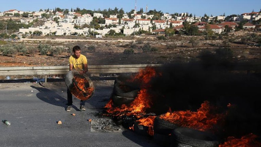 Un jeune palestinien enflamme des pneus dans le camp de Jalazoun près de Ramallah pour bloquer l'accès de la route aux Israéliens, le 24 octobre 2014