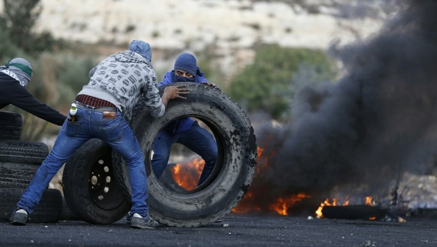 Des Palestiniens déplacent des pneus pour les faire brûler lors de heurts avec les forces de sécurité israéliennes, le 27 octobre 2015 près de Ramallah, en Cisjordanie