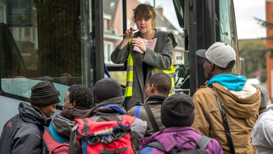 Une femme s'adresse aux migrants avant leur montée dans un bus qui va les transporter de Calais à des centre de "répit", le 27 octobre 2015