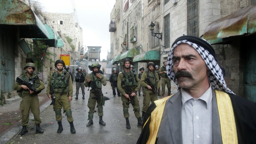 Un palestinien face à des membres des forces de sécurité israéliennes, le 27 octobre 2015 à Hébron, en Cisjordanie occupée