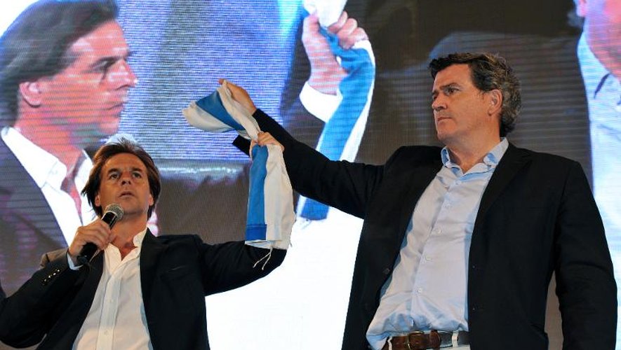 Luis Lacalle Pou (g), candidat du Parti national, et Pedro Bordaberry, candidat du Parti Colorado, tiennent le drapeau national à l'occasion des élections générales, le 26 octobre 2014 à Montevideo