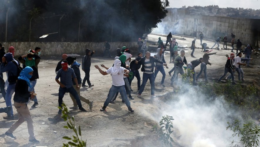 Des Palestiniens jettent des pierres aux forces armées israéliennes près du mur érigé par Israël entre Jérusalem et la ville d'Abu Dis, en Cisjordanie, le 28 octobre 2015