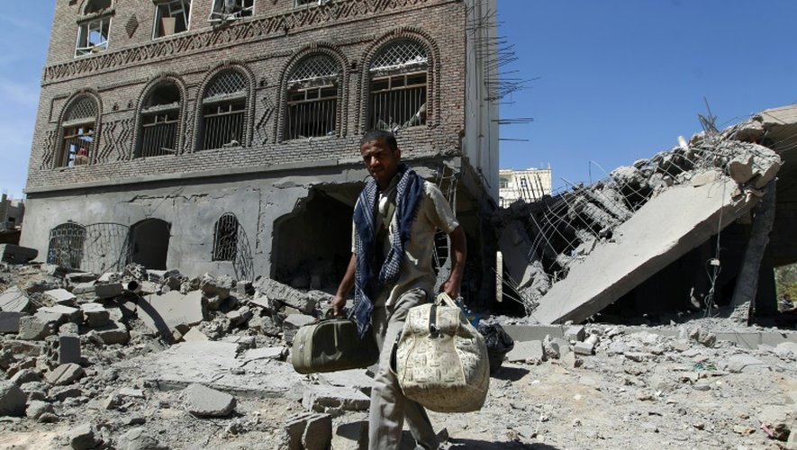 Un homme transporte ses affaires à travers les ruines de bâtiments détruits par la coalition dirigée par l'Arabie saoudite, à Sanaa le 28 octobre 2015