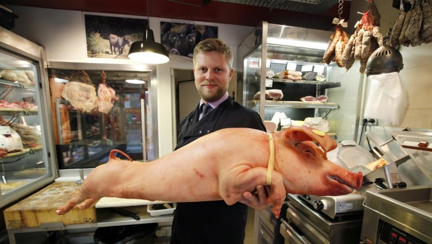 Le boucher Bastien Nicolas pose avec un porc dans sa boutique "Terroirs d'avenir" à Paris, le 28 octobre 2015