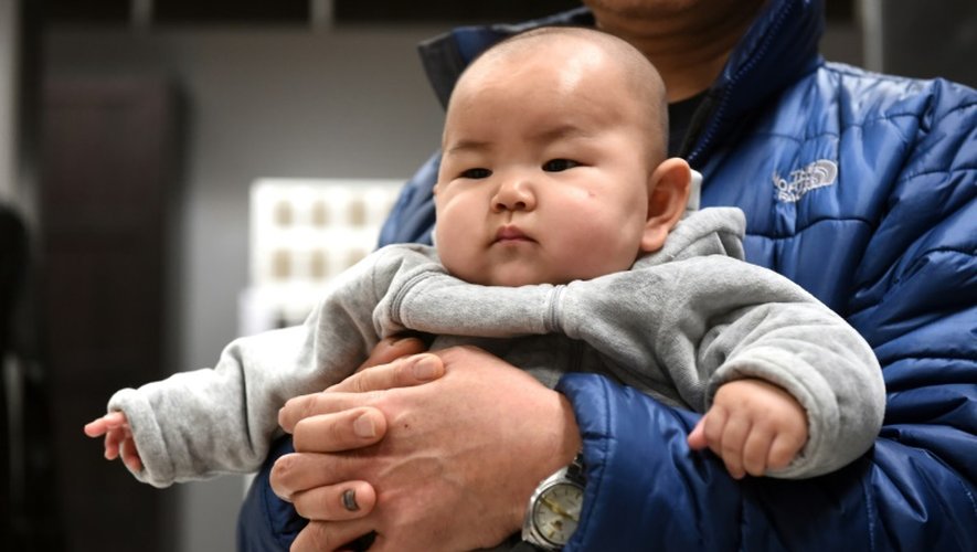 Un bébé chinois dans les bras de son père le 19 janvier 2015 à Pékin