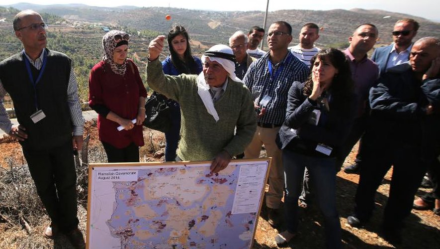 Un agriculteur palestinien explique aux envoyés des Nations Unies et défenseurs des droits palestiniens les restrictions d'accès aux champs d'oliviers, près du village d'Al-Janiya, le 28 octobre 2014