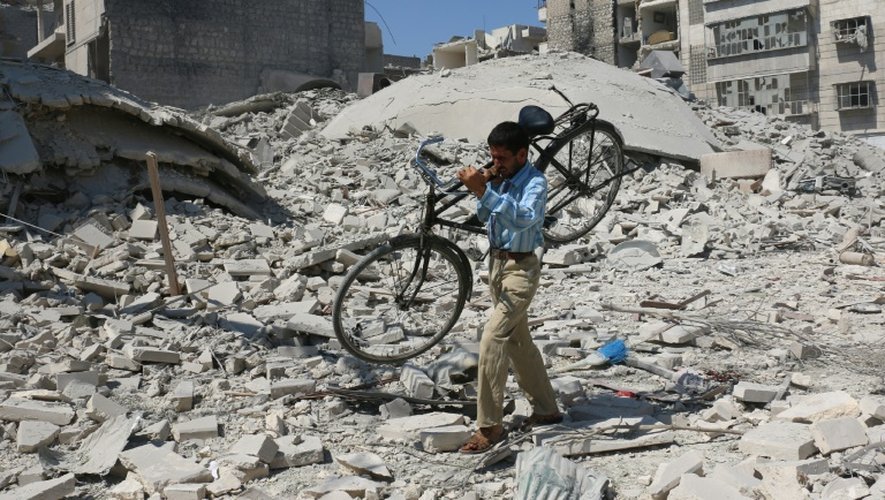Un homme transporte un vélo parmi les ruines de bâtiments bombardés dans le nord d'Alep, le 11 septembre 2016