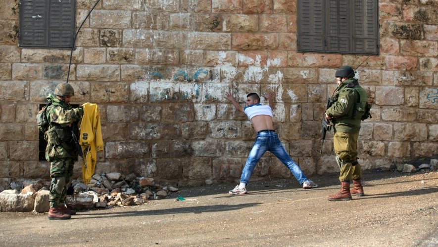 Des soldats israéliens fouillent un Palestinien près de la colonie juive de Beit Hadassah, au centre d'Hébron, le 29 octobre 2015