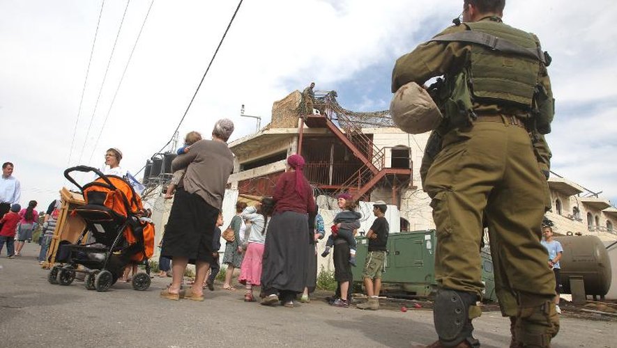 Un soldat israélien surveille l'installation de colons israéliens dans un immeuble de quatre étages qu'une famille palestinienne revendique depuis des années à Hébron accusant les colons d'acquisition frauduleuse, en Cisjordanie le 13 avril 2014