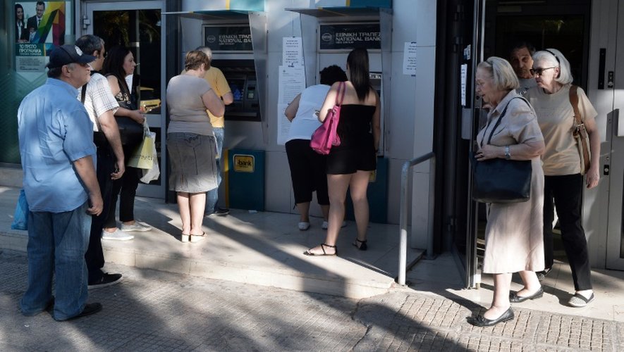 Des Grecs patientent devant un distributeur pour retirer de l'argent à Athènes, le 20 juillet 2015