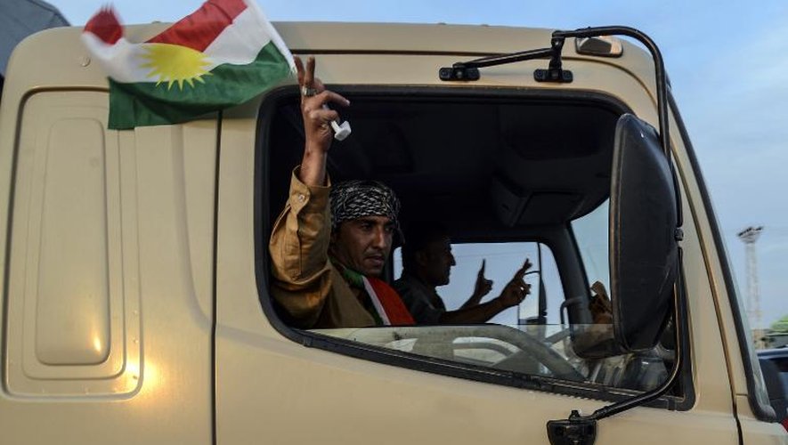 Des combattants kurdes irakiens agitent le drapeau du Kurdistan à Viransehir, dans la province de Sanliurfa, en route pour défendre la ville syrienne de Kobané, le 29 octobre 2014