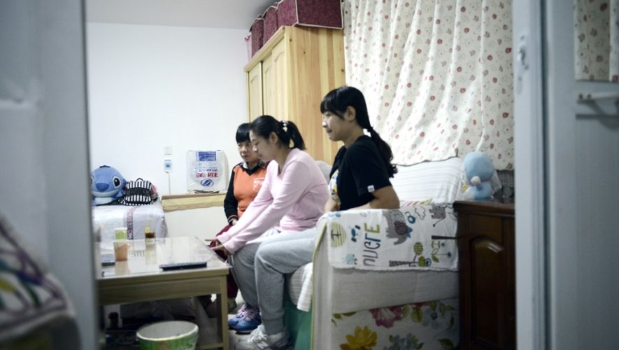 Li Xue chez elle à Pékin, le 31 octobre 2015, avec sa soeur Li Bin (d) et sa mère Bai Xiuling (g)