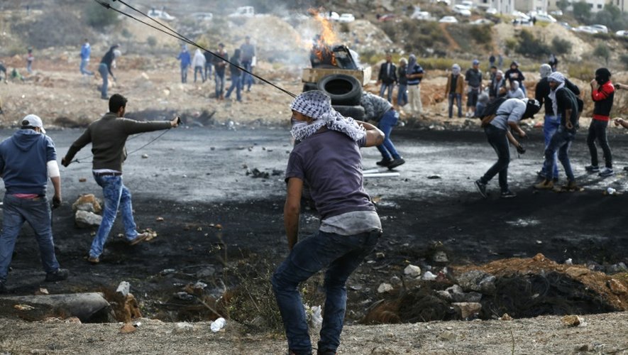 Des Palestiniens lancent des pierres vers des soldats israéliens dans les environs de Ramallah, le 27 octobre 2015