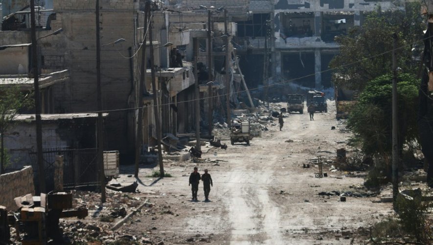 Des combattants syriens pro-régime empruntent une rue de la ville d'Alep ravagée par les bombardements, le 9 septembre 2016