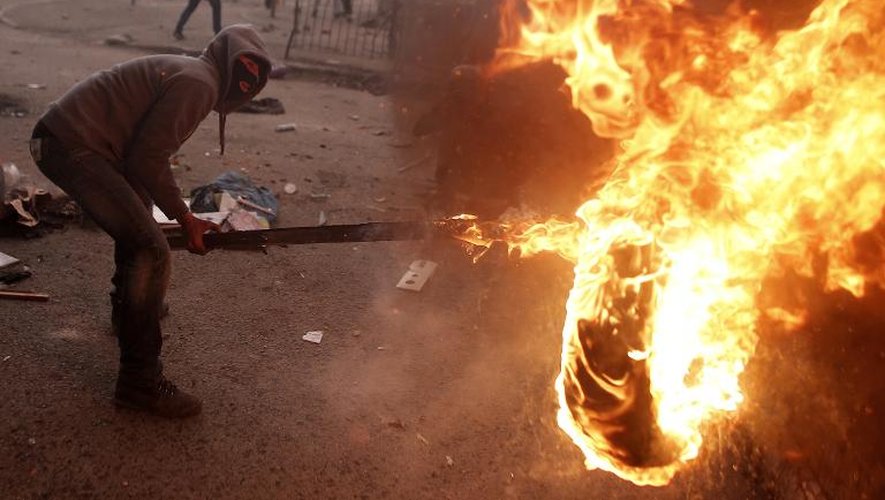 Un manifestant palestinien près d'un pneu en feu lors d'affrontement avec les forces de sécurité israéliennes à Jérusalem le 5 novembre 2014