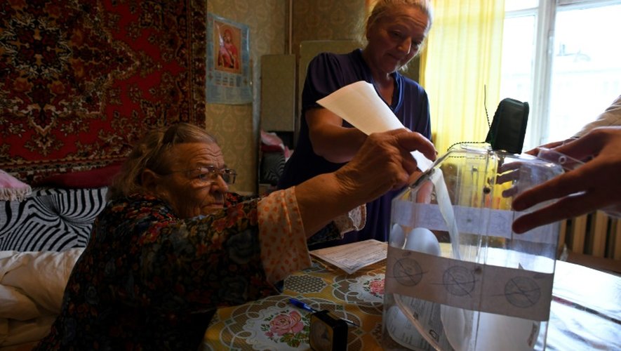 Une personne âgée dépose son bulletin de vote dans une urne apportée à son domicile à Moscou