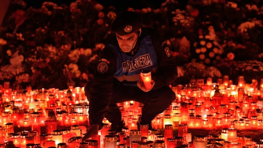 Un gendarme roumain place des bougies en mémoire des victimes de l'incendie d'une discothèque à Bucarest le 2 novembre 2015