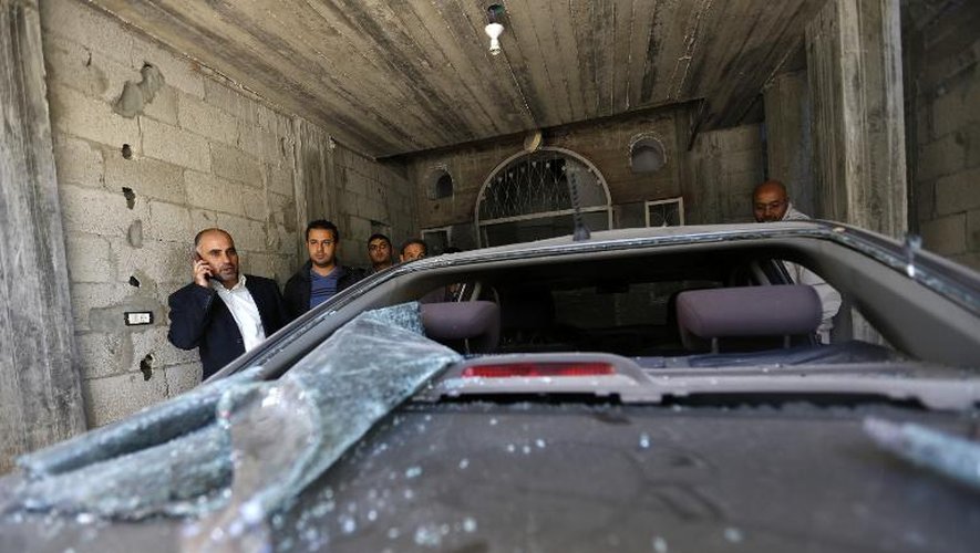 Le leader du Fatah, Fayez Abu Eitta (g), au téléphone, inspecte les dégâts causés à son véhicule dans le parking de sa maison à Beit Lahya, dans la bande de Gaza, le 7 novembre 2014